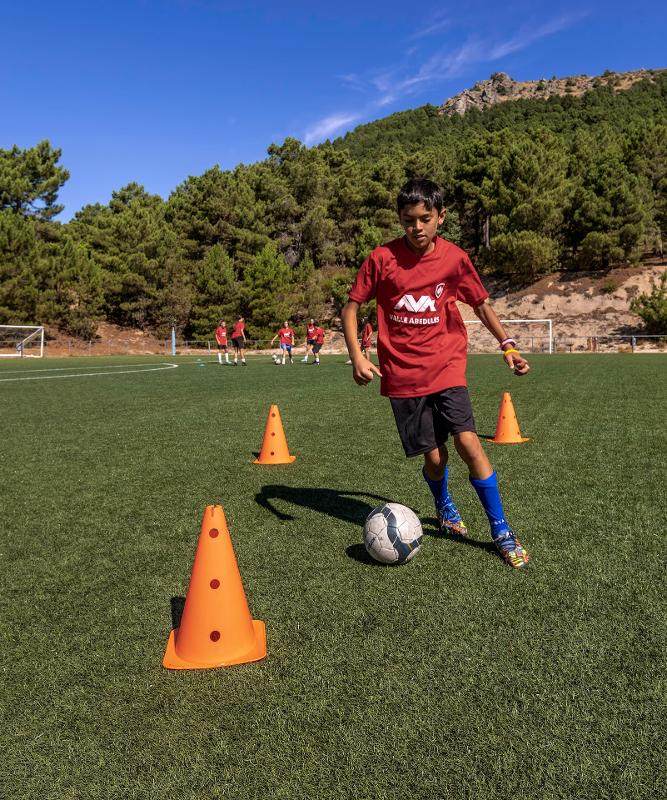 Un niño practicando técnicas de futbol en un campamento de futbol en madrid