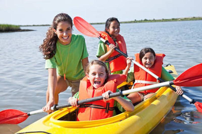 Un grupo de niñas en un kayak en medio de un lago en un campamento ingles madrid