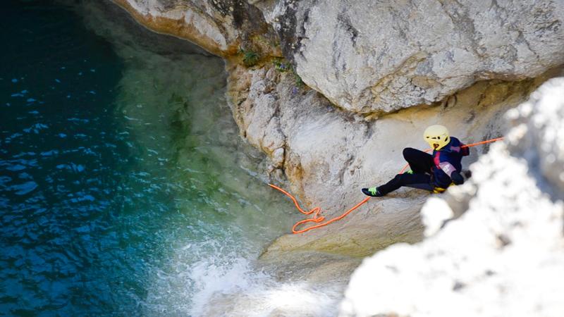 Disfruta de aventuras en un campamento jaen Una foto de una persona bajando a un barranco con una cuerda en un campamento jaen