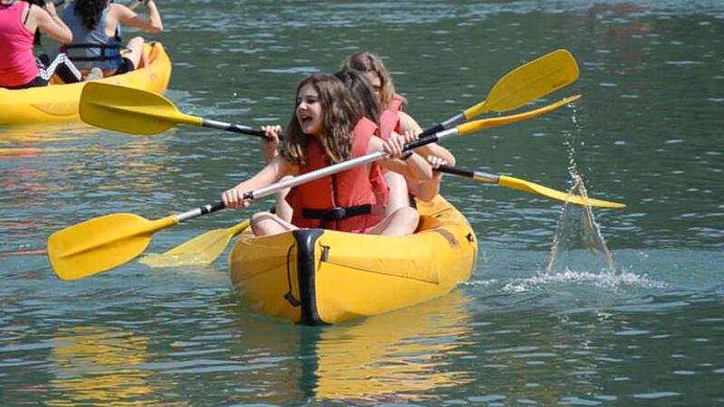 Disfruta de los kayaks en un campamento jaen con tus amigos Chicas haciendo kayak en un campamento jaen