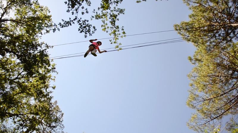 Descubre deportes como slackline en un campamento multiaventura Una niña practicando slackline en un campamento multiaventura