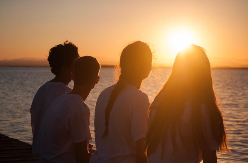 la foto de un grupo de jovenes disfrutando del atardecer en un campamento de verano en valencia