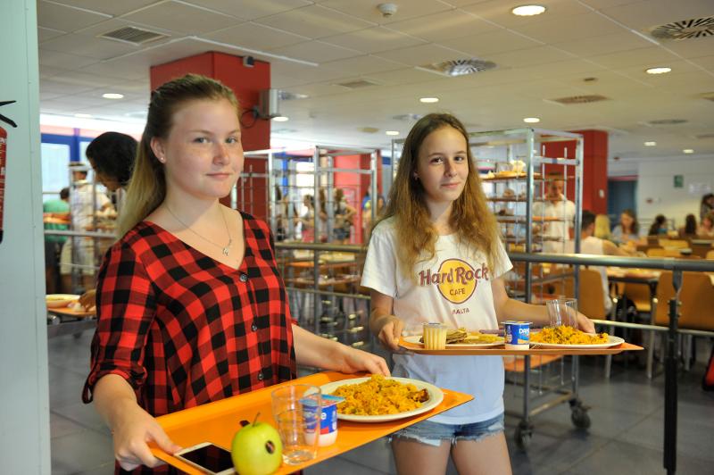 Dos chicas en un comedor comiendo paella en un campamento verano valencia