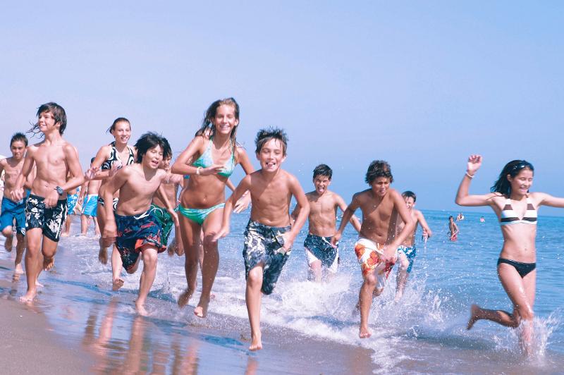 Un grupo de niños corriendo y jugando en la playa en un campamento de verano malaga