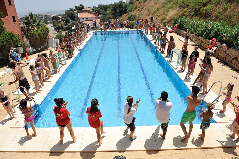 Un grupo de jovenes y niños en el borde de una piscina en un campamento de verano marbella