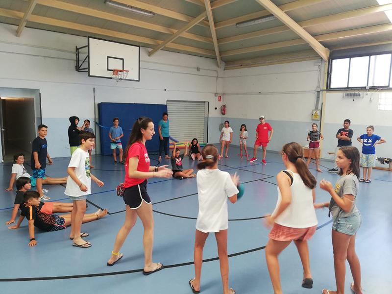 Un grupo de niños jugando en una pista de baloncesto en un campamento de verano en marbella