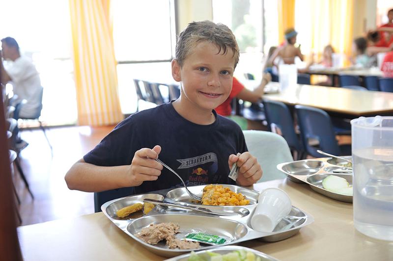 Un niño sonriendo a camara en un comedor de un campamento de verano en marbella