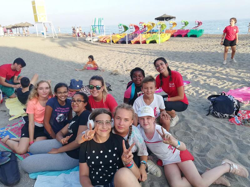 un grupo de niños en una playa sonriendo a camara en un campamento de verano en marbella