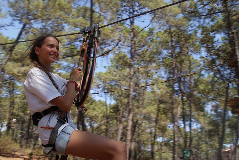 Una niña haciendo tirolina en un campamento verano marbella