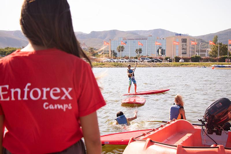 Un chico practicando paddle surf en un campamento de verano