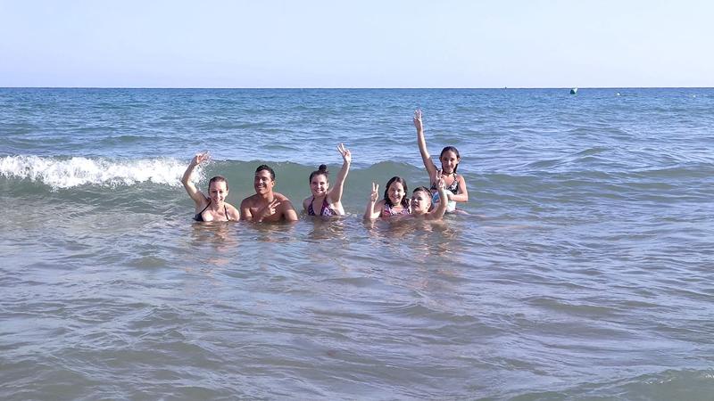 Un grupo de jovenes en la playa nadando en un campamento verano
