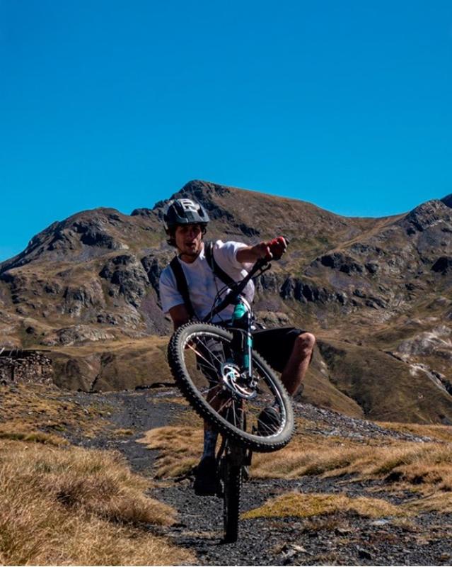Joven haciendo acrobacias con una bici en unas vacaciones ski