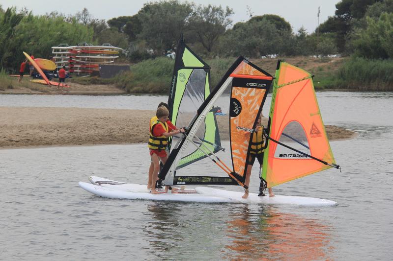 Un grupo de niños practicando windsurf en un campamento de verano