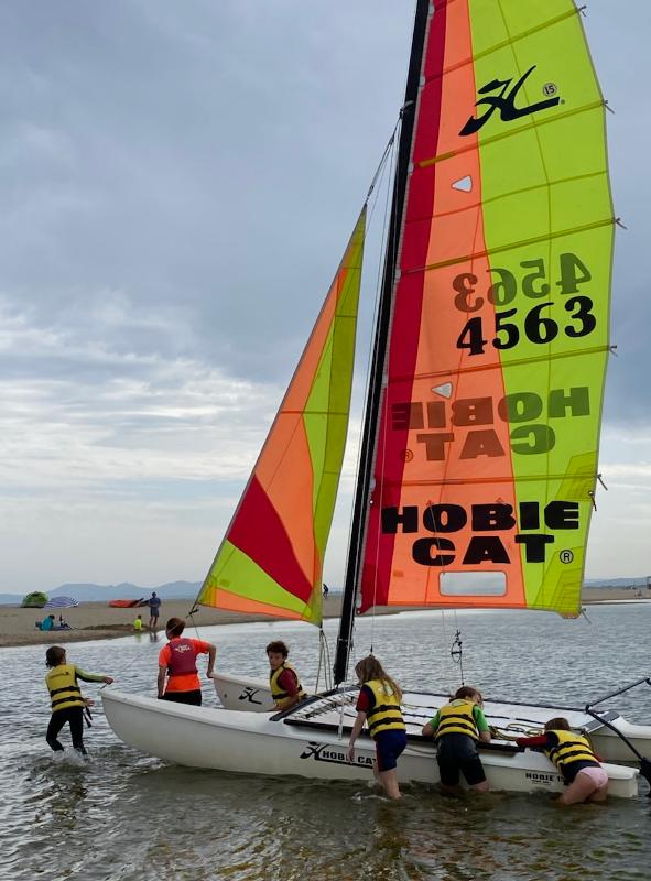 Un grupo de niños en un barco en un campamento de windsurf