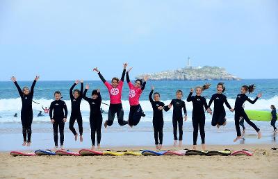 Grupo de niños celebrando su jornada de surf en la playa en el campamento de verano en Cantabria