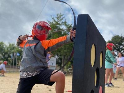 Niño aprendiendo a tirar con arco durante un campamento verano multiaventura