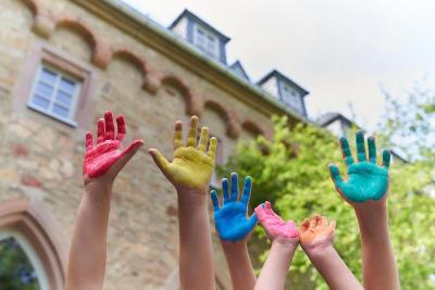 Niños subiendo sus manos pintadas de colores durante un taller creativo en un curso verano alemania