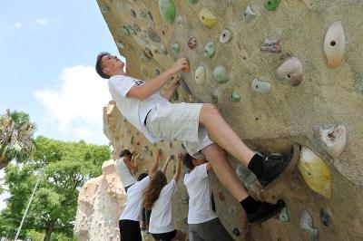 Una foto de un chico escalando un rocodromo en un campamento verano valencia