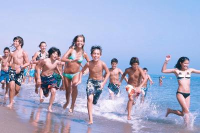 Un grupo de niños corriendo y jugando en la playa en un campamento de verano malaga